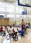 Players in wheelchairs gather around a hoop in during a wheelchair basketball game.