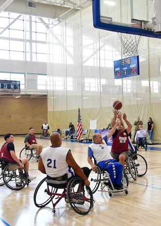 Players in wheelchairs gather around a hoop in during a wheelchair basketball game.