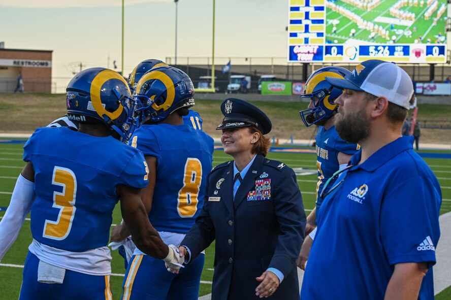 U.S. Air Force Col. Angelina Maguinness, 17th Training Wing Commander shakes hands with Andrew Pitts, Angelo State University cornerback, before the start of the annual Angelo State University Military Appreciation Game at the 1st Community Credit Union Field at LeGrand Stadium, San Angelo, Texas, Nov. 2, 2024. Angelo State invited all military members, veterans and Department of Defense ID holders to attend their football game against Central Washington University. (U.S. Air Force photo by Airman 1st Class James Salellas)