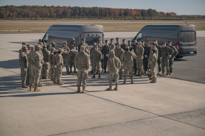 A large group of Marines and Airmen stand on a flightline after a dignified transfer ground training.