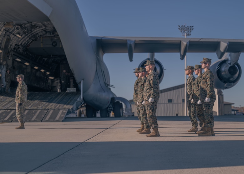 A group of Marines and one Airman stand at attention on a flightline during a dignified transfer ground training.