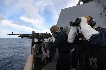 GM2 Delair Morgan, right, looks through binoculars as FC2 Nathan Ritchie fires an M240B machine gun during a live-fire weapons exercise aboard USS Dewey (DDG 105) in the Andaman Sea.