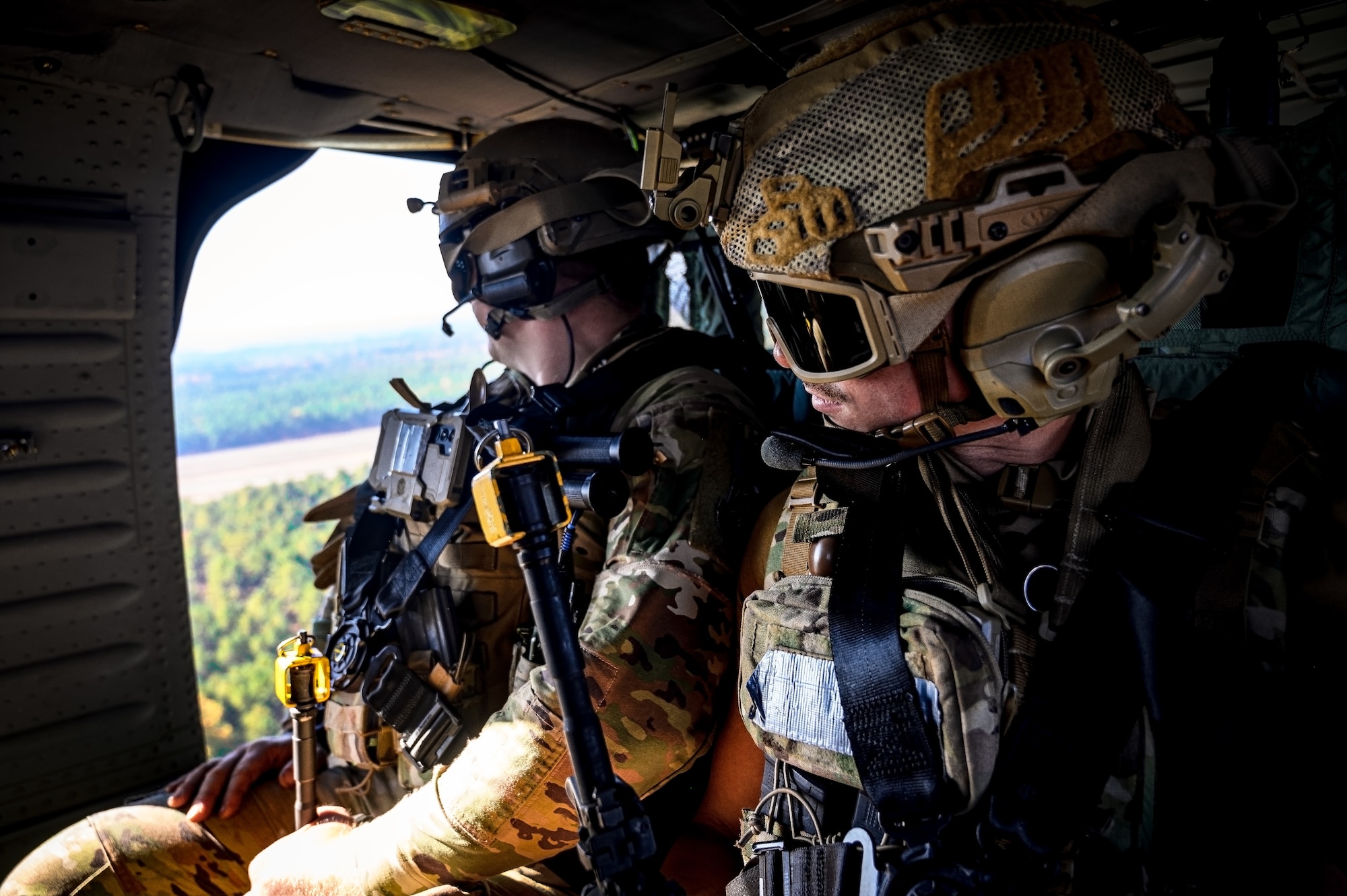 U.S. Air Force Senior Airman Clayton Gagliastri, 87th Civil Engineer Squadron explosive ordinance technician, and Tech. Sgt. Matt Morris, 87th Civil Engineer Squadron explosive ordinance technician, are transported on a Sikorsky UH-60 Black Hawk helicopter during Operation Honey Badger at Joint Base McGuire-Dix-Lakehurst, N.J., Oct. 22, 2024. The New Jersey Army National Guard provided aerial support to assist with sling load operations for the aviators and loadmasters participating in the exercise. (U.S. Air Force photo by Senior Airman Matt Porter)