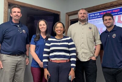 Two women and three men stand together facing the camera