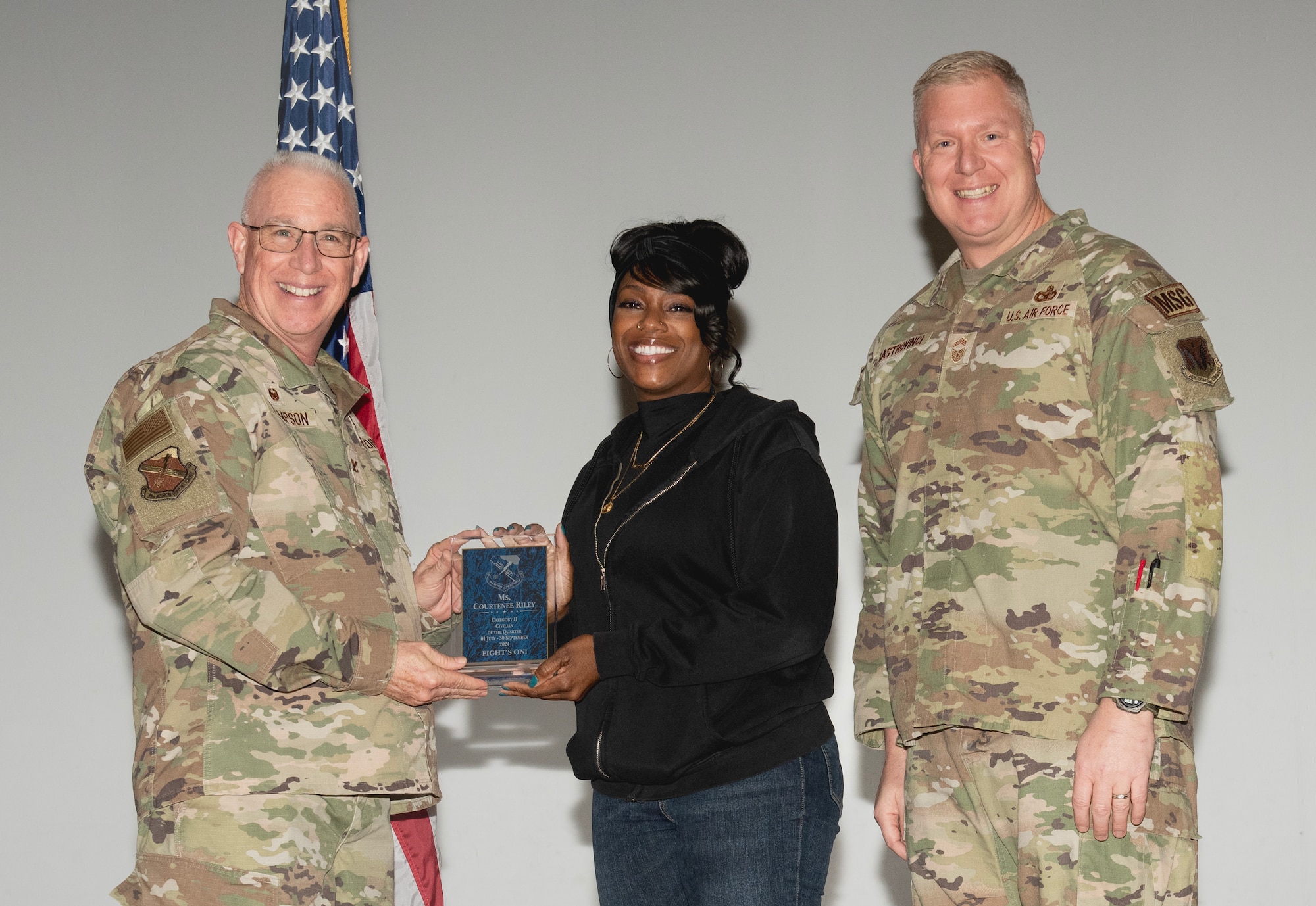 U.S. Air Force Col. Harley P. Thompson, left, commander of the 99th Mission Support Group (MSG), and Chief Master Sgt. Scott Castrovinci, Senior Enlisted Leader of the 99th MSG, right, present the Category II Civilian of the Quarter award to Courtenee Riley, a network engineer assigned to the 99th Communications Squadron, during the third quarter awards at Nellis Air Force Base, Nevada, Oct. 29, 2024.