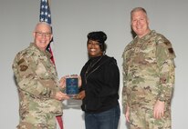 U.S. Air Force Col. Harley P. Thompson, left, commander of the 99th Mission Support Group (MSG), and Chief Master Sgt. Scott Castrovinci, Senior Enlisted Leader of the 99th MSG, right, present the Category II Civilian of the Quarter award to Courtenee Riley, a network engineer assigned to the 99th Communications Squadron, during the third quarter awards at Nellis Air Force Base, Nevada, Oct. 29, 2024.