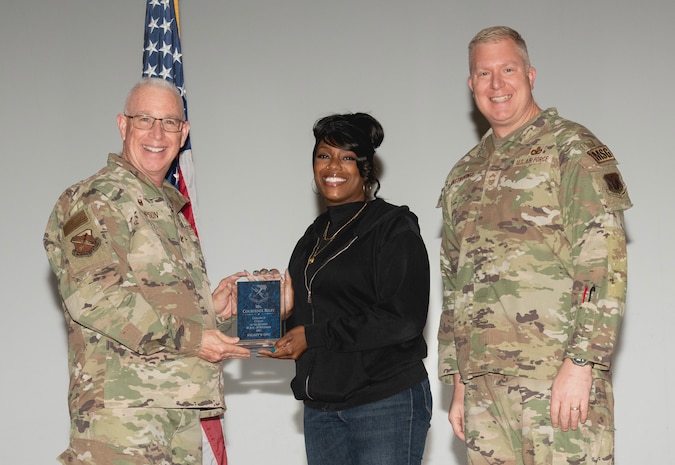U.S. Air Force Col. Harley P. Thompson, left, commander of the 99th Mission Support Group (MSG), and Chief Master Sgt. Scott Castrovinci, Senior Enlisted Leader of the 99th MSG, right, present the Category II Civilian of the Quarter award to Courtenee Riley, a network engineer assigned to the 99th Communications Squadron, during the third quarter awards at Nellis Air Force Base, Nevada, Oct. 29, 2024.