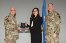 U.S. Air Force Col. Harley P. Thompson, left,  commander of the 99th Mission Support Group (MSG), and Chief Master Sgt. Scott Castrovinci, Senior Enlisted Leader of the 99th MSG, right, present the Category III Civilian of the Quarter award to Angela Mendoza, a contracting officer, construction team lead assigned to the 99th Contracting Squadron, during the third quarter awards at Nellis Air Force Base, Nevada, Oct. 29, 2024.