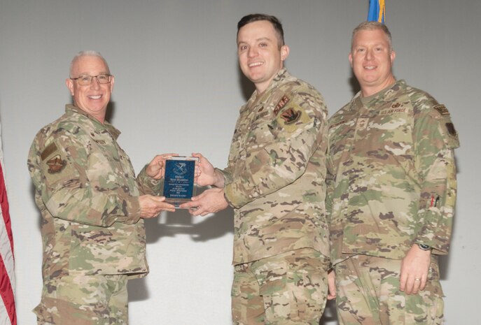 U.S. Air Force Col. Harley P. Thompson, left, commander of the 99th Mission Support Group (MSG), and Chief Master Sgt. Scott Castrovinci, Senior Enlisted Leader of the 99th MSG, right, present a Senior noncommissioned Officer of the Quarter award to Senior Master Sgt. Sean Bambino, a superintendent assigned to the 99th Logistics Readiness Squadron,  during the third quarter awards at Nellis Air Force Base, Nevada, Oct. 29, 2024.