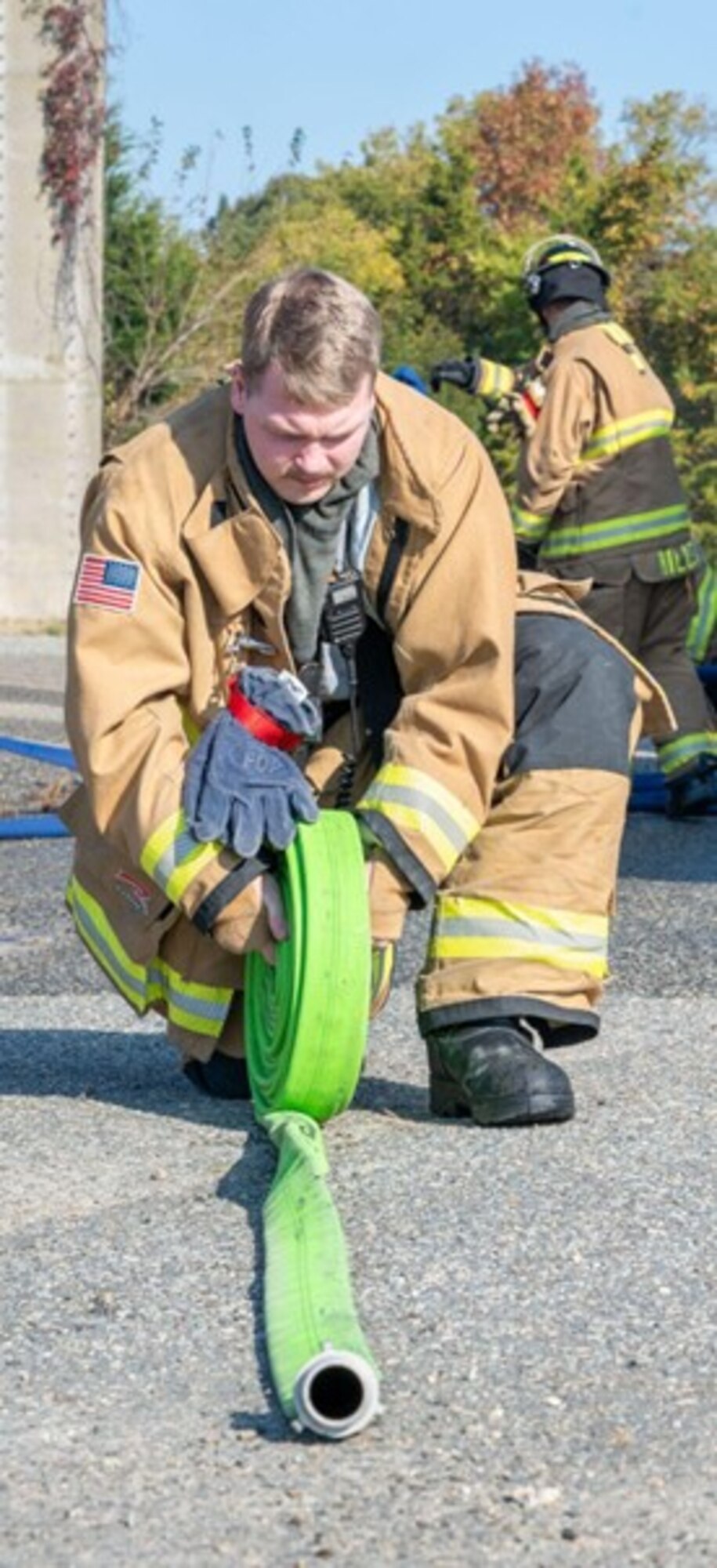 Firefighter rolls up a water hose. (U.S. Air Force photo by Airman Donnell Ramsey)