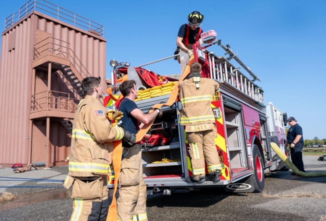 Firefighters put away hose on firetruck. (U.S. Air Force photo by Airman Donnell Ramsey)