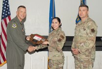 U.S. Air Force Col. Dane J. Gehrmann, left, commander of the Nevada Test and Training Range (NTTR), and Senior Master Sgt. Dennis Kolesnik, right, senior enlisted leader assigned to NTTR, present the Airman of the Quarter to Airman 1st Class Alexandria Salinas, an executive administrator assigned to NTTR during a commander’s call at Nellis Air Force Base, Nevada, Oct. 31, 2024.