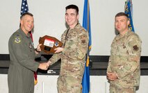 U.S. Air Force Col. Dane J. Gehrmann, left, commander of the Nevada Test and Training Range (NTTR), and Senior Master Sgt. Dennis Kolesnik, right, senior enlisted leader assigned to NTTR, present the Senior Noncommissioned Officer of the Quarter award as 1st Lt. Rayne Jones, a battlespace engineer assigned to the 31st Combat Training Squadron, accepts on behalf of Master Sgt. Brittnay Mosley, during a commander’s call at Nellis Air Force Base, Nevada, Oct. 31, 2024.