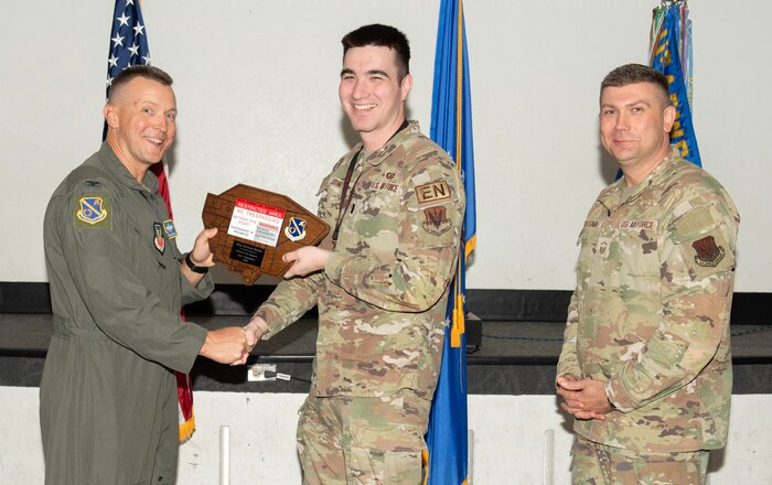 U.S. Air Force Col. Dane J. Gehrmann, left, commander of the Nevada Test and Training Range (NTTR), and Senior Master Sgt. Dennis Kolesnik, right, senior enlisted leader assigned to NTTR, present the Senior Noncommissioned Officer of the Quarter award as 1st Lt. Rayne Jones, a battlespace engineer assigned to the 31st Combat Training Squadron, accepts on behalf of Master Sgt. Brittnay Mosley, during a commander’s call at Nellis Air Force Base, Nevada, Oct. 31, 2024.