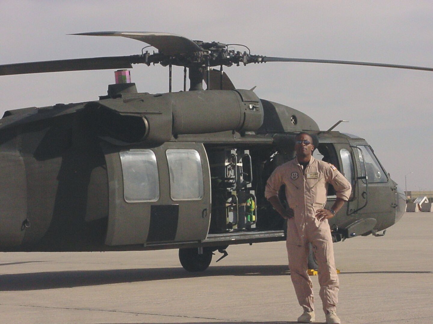 Dean Newsome wears a flight suite and stand by a Helicopter.