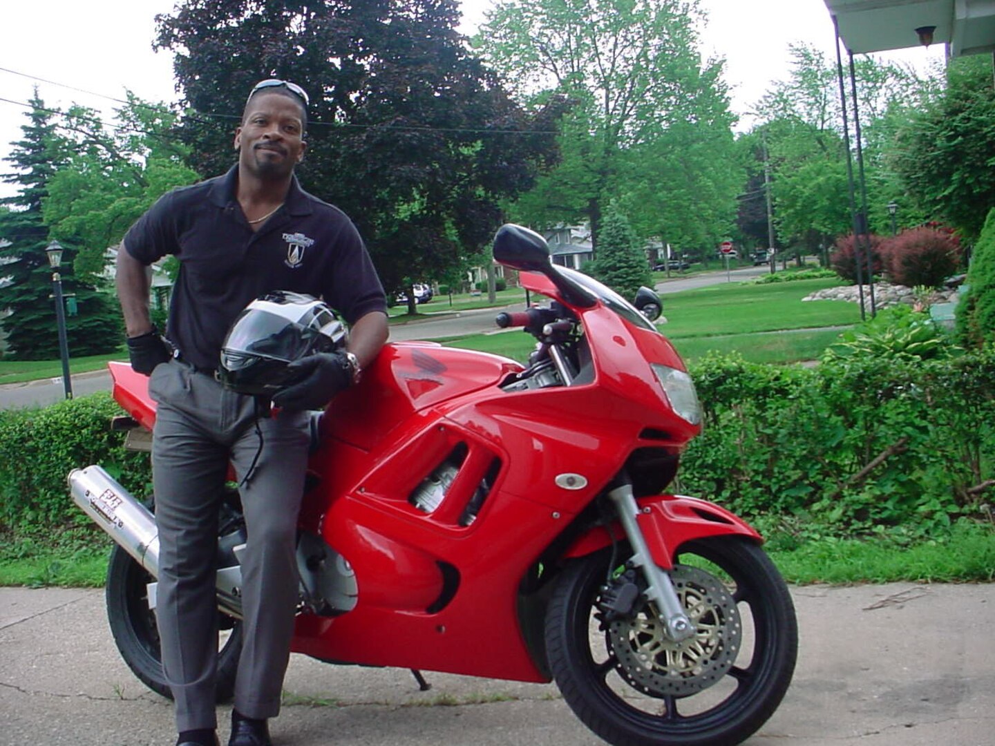 Dean Newsome stands next to a red motorcycle.