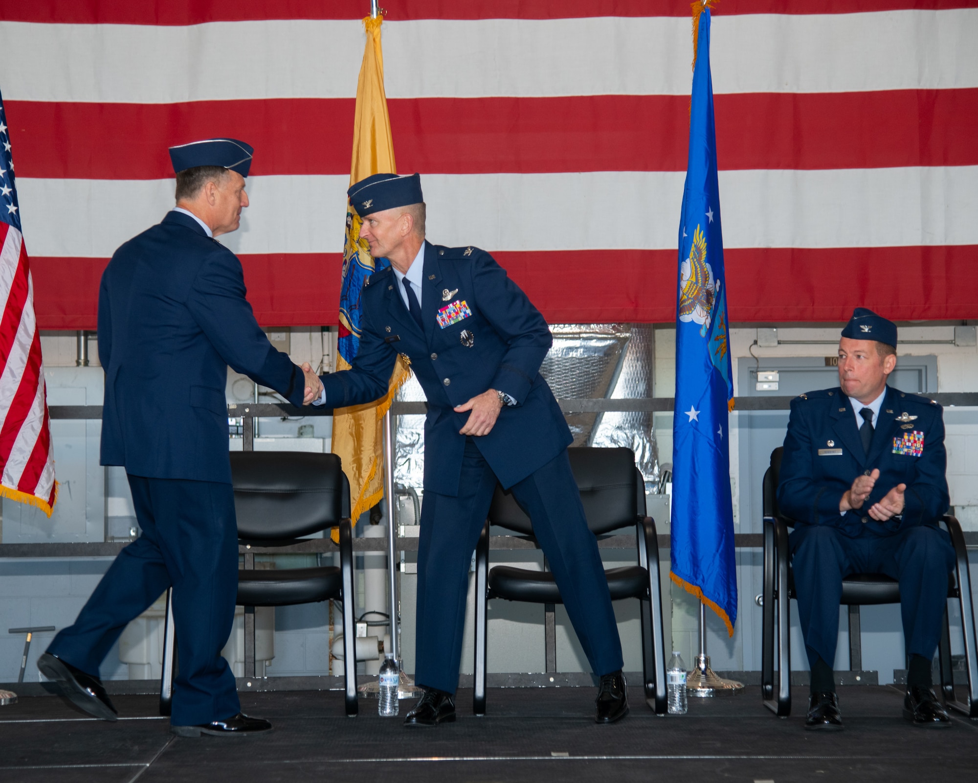 Two men shake hands on a stage.