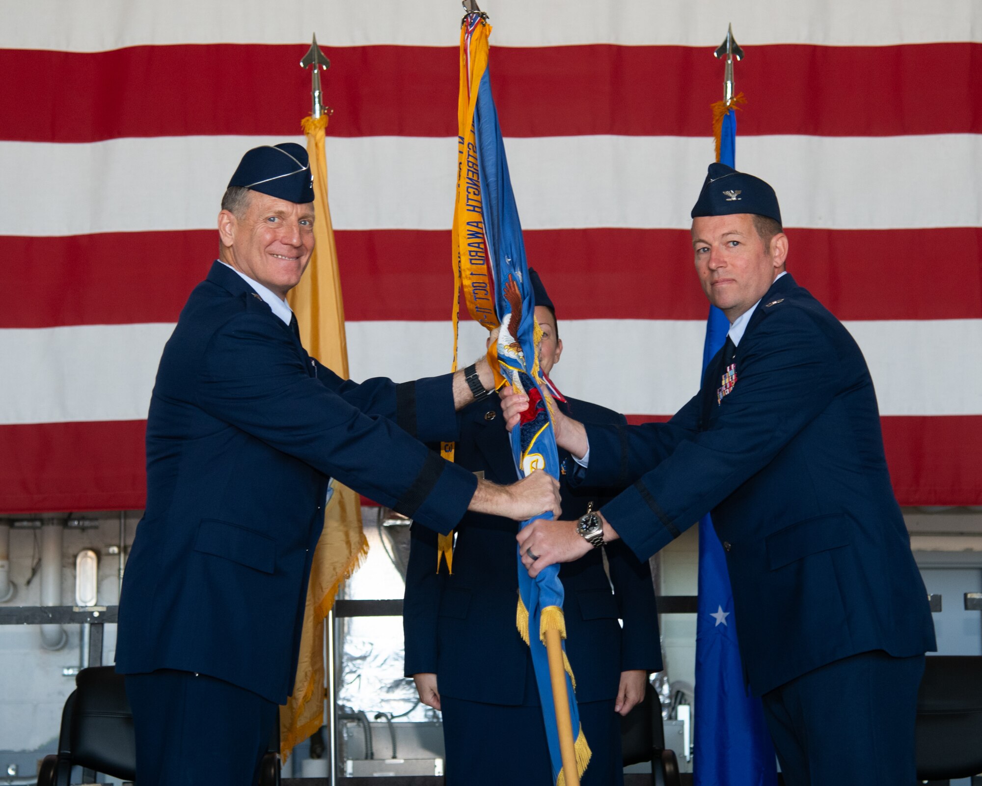 Two men hold a guide-on banner flag and look towards the camera.