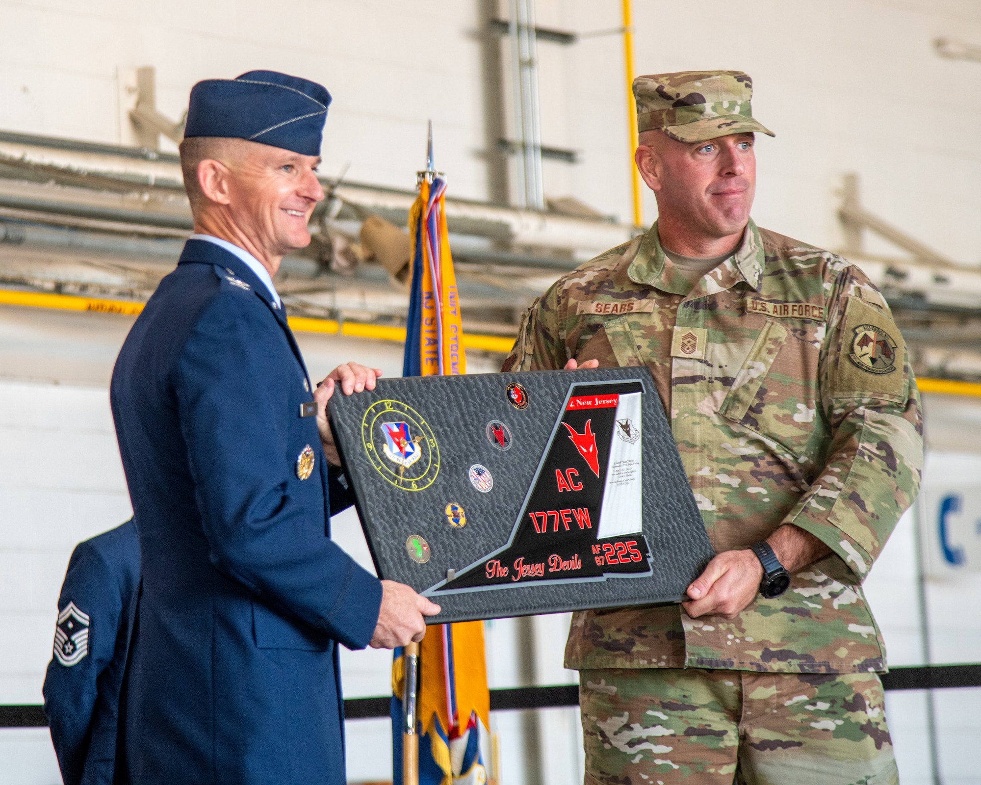 Two men hold an award plaque.