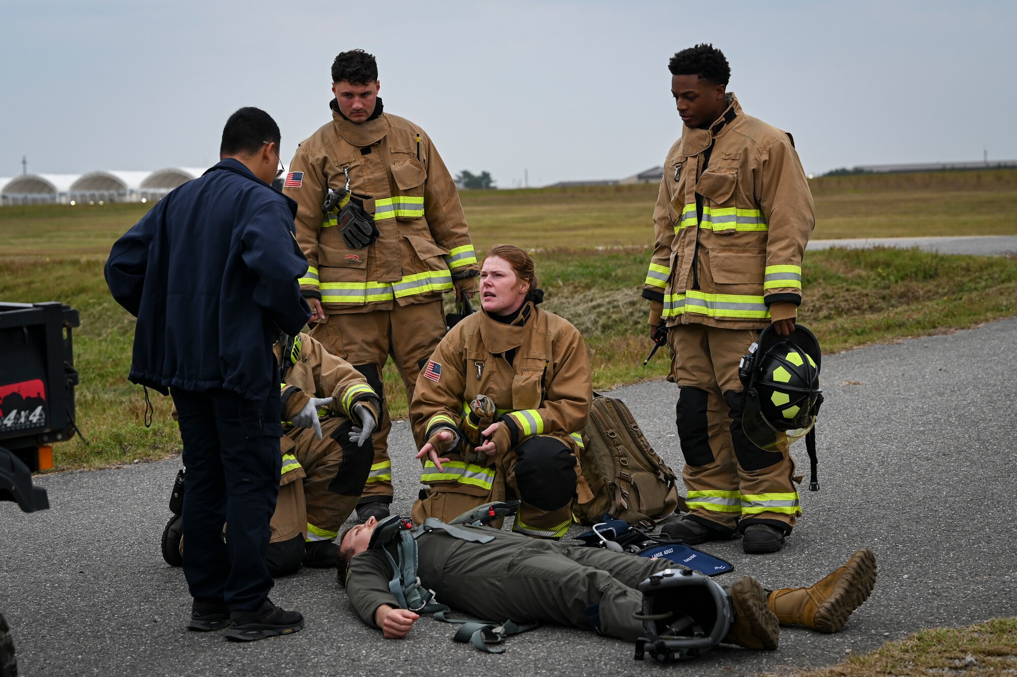U.S. Air Force firefighters, assigned to the 8th Civil Engineer Squadron, report the status of a simulated injured pilot to medical personnel during a mass accident response exercise.
