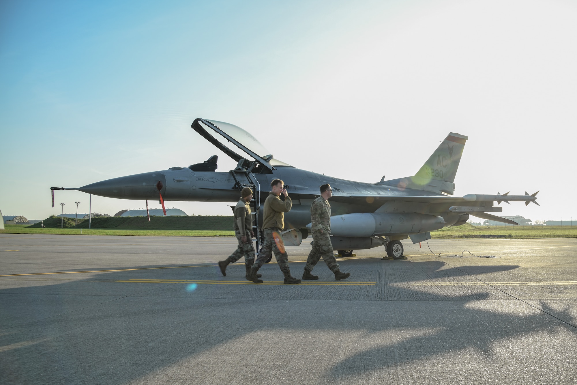 An F-16C sits on display on a flightline during the sunrise.