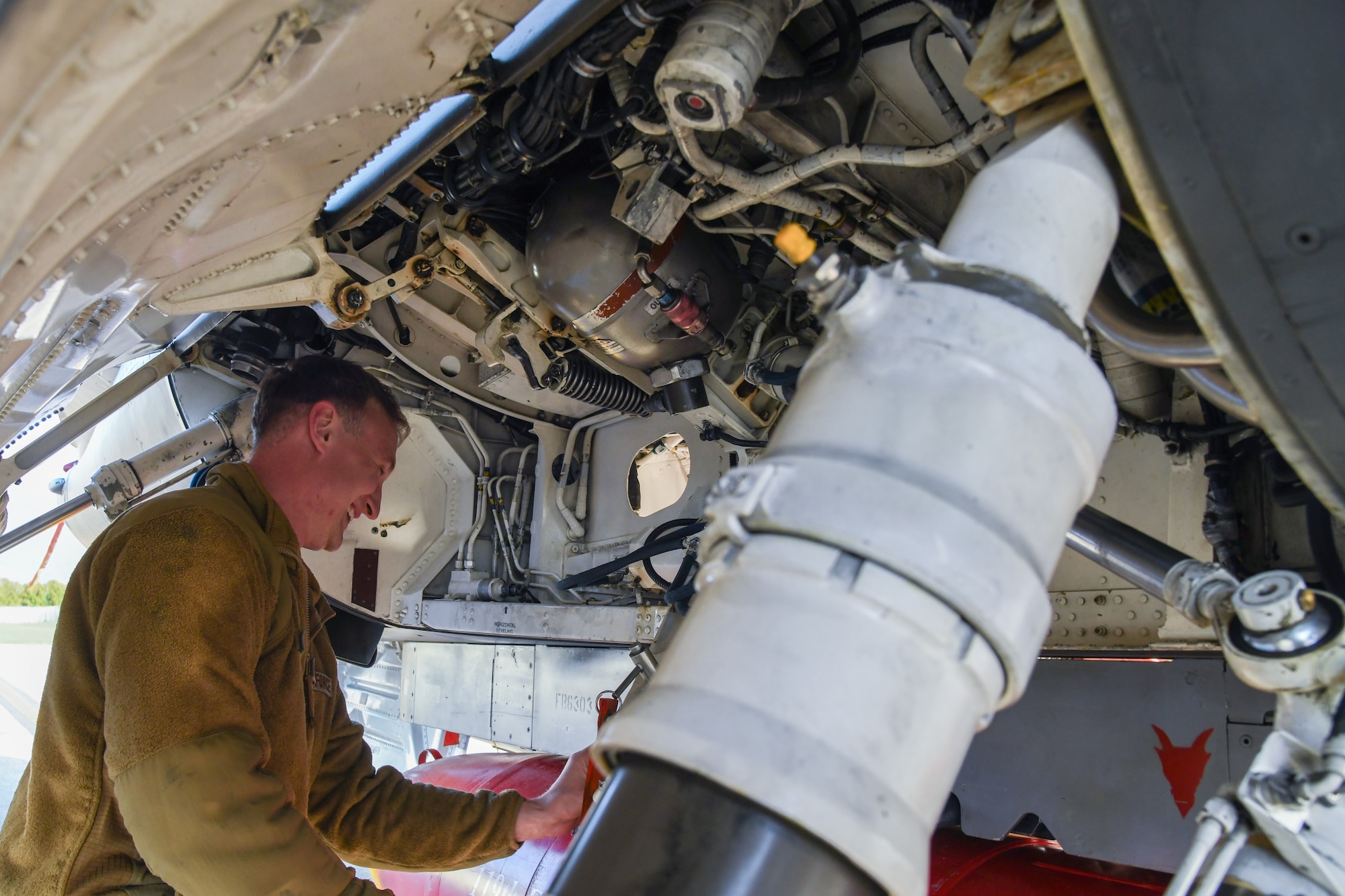 An aircraft mechanic works under an F-16C fighter jet.