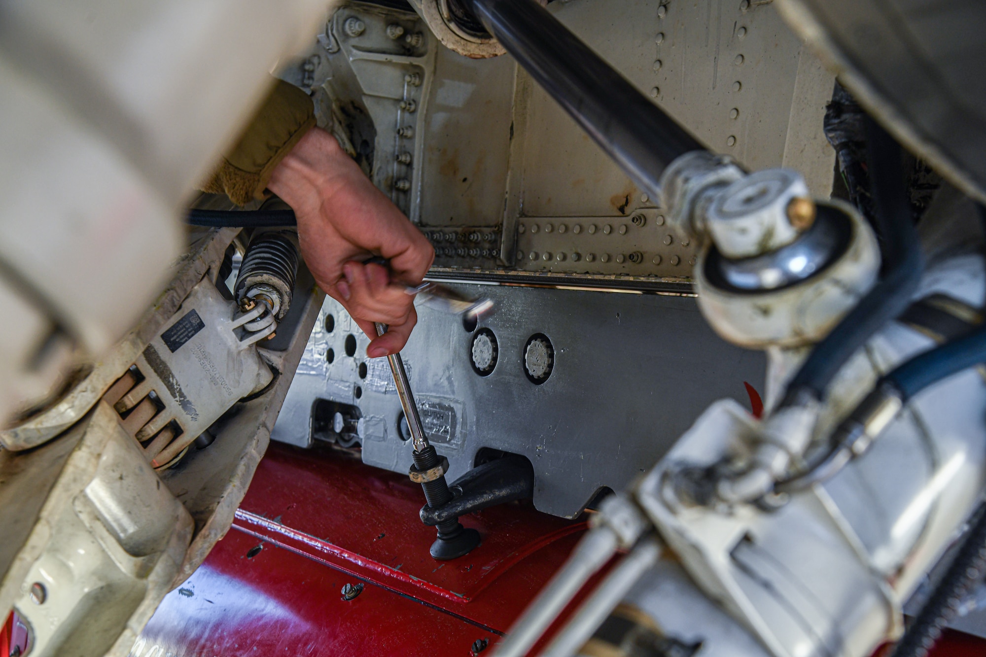 An aircraft mechanic works under an F-16C fighter jet.