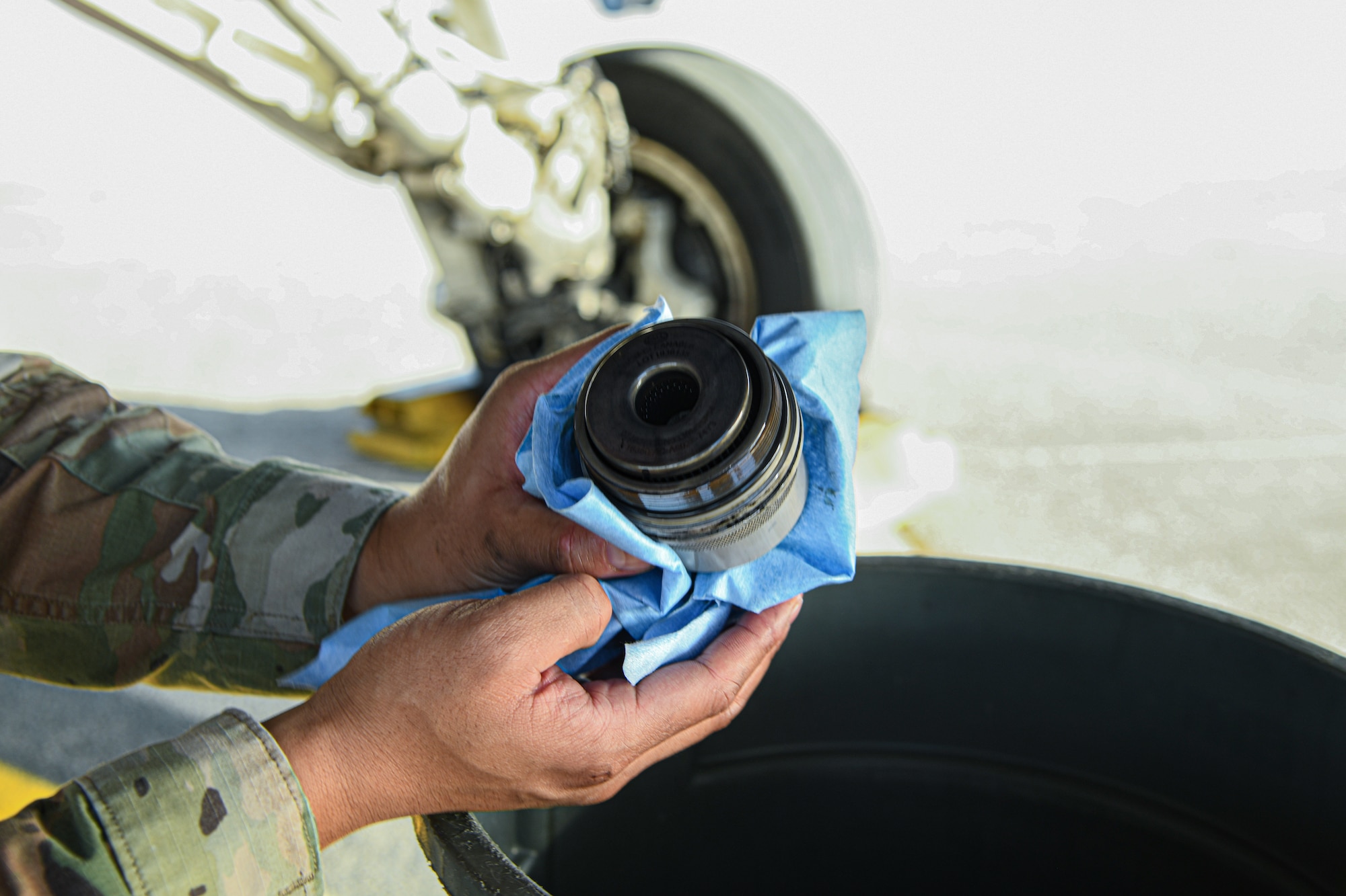 An Airman holds a piece of a fighter jet close to the camera lens.