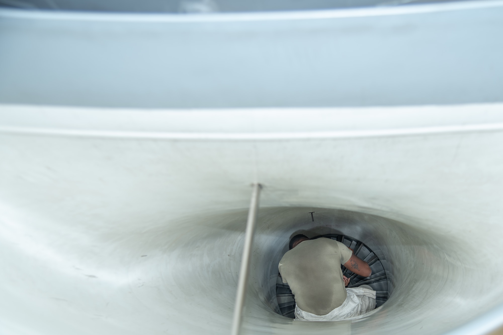 An Airman sits inside the intake of an F-16C fighter jet.
