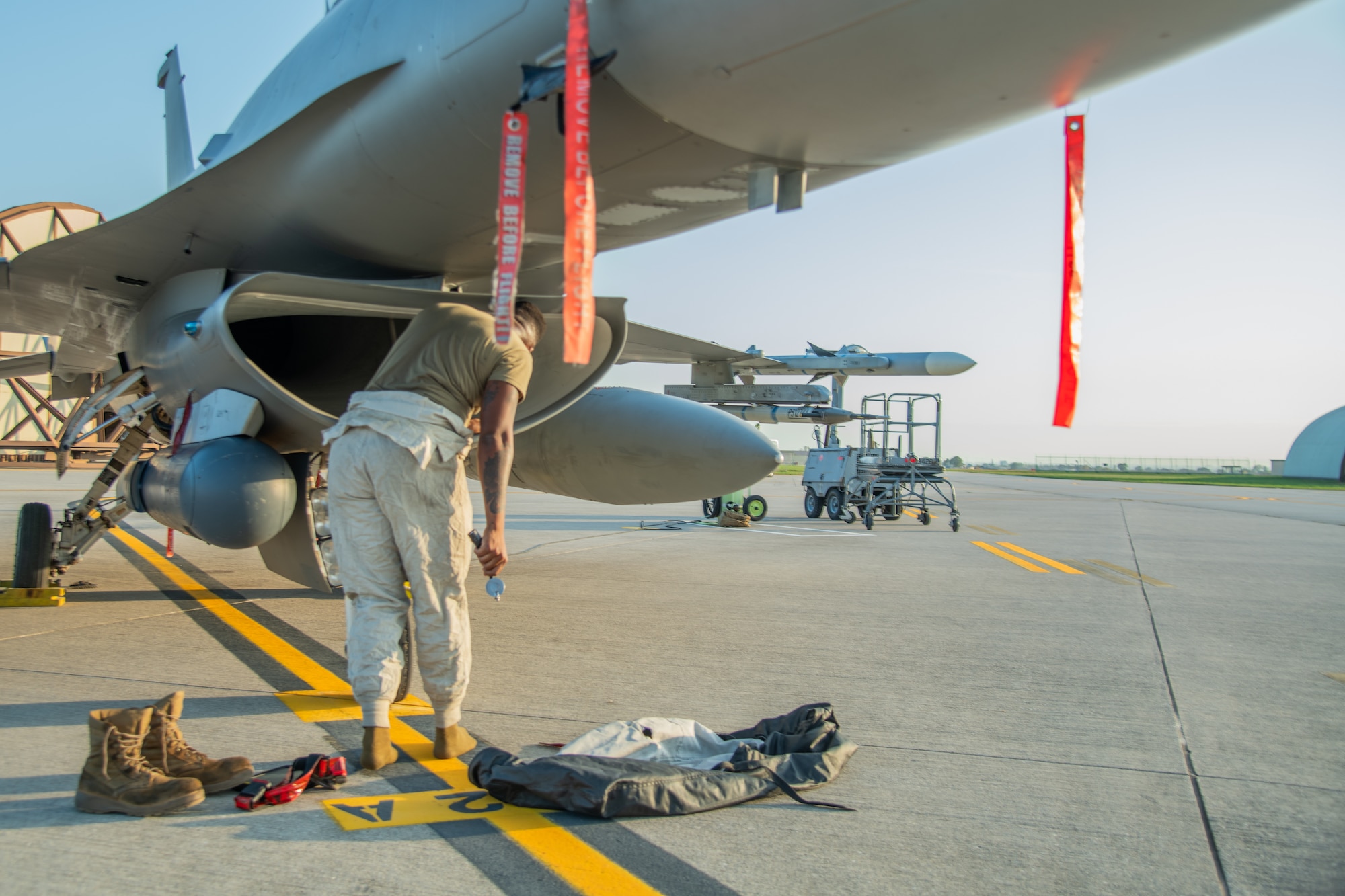 An Airman stands in front an F-16C fighter jet.