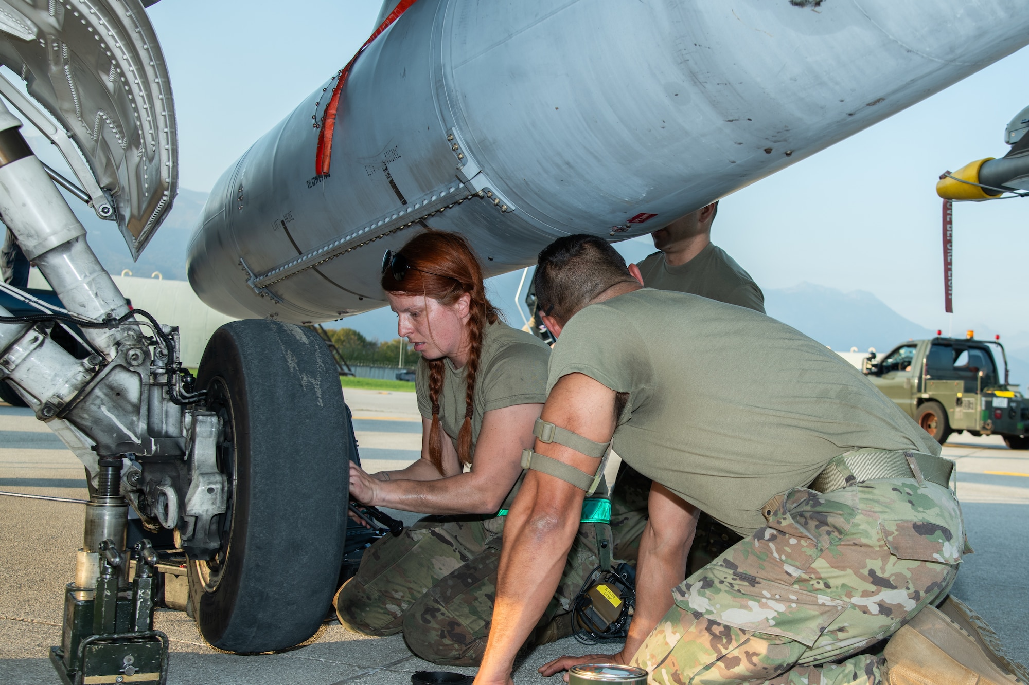 Two Airman change the tire of an F-16C fighter jet.