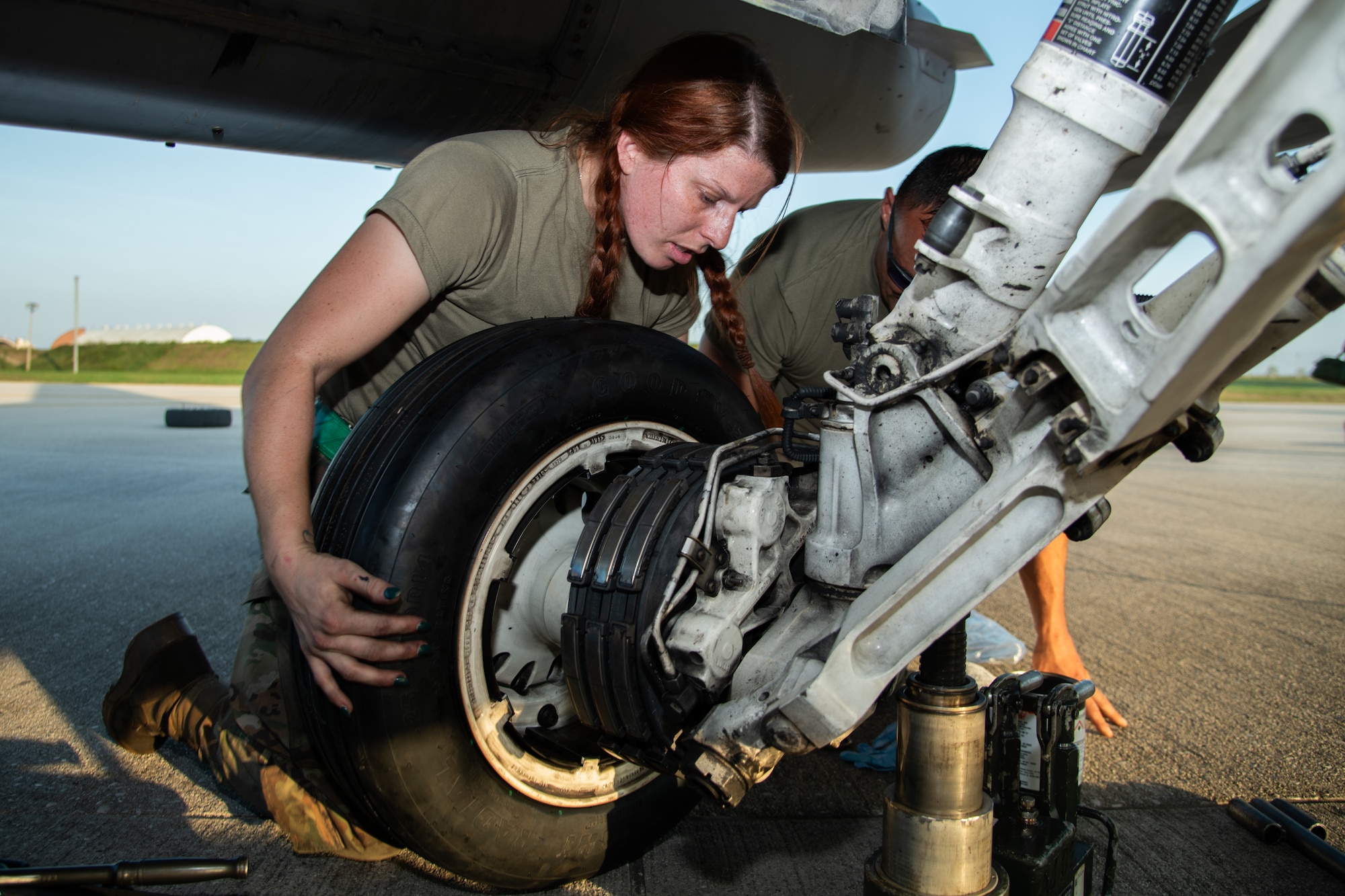 Two Airman change the tire of an F-16C fighter jet.