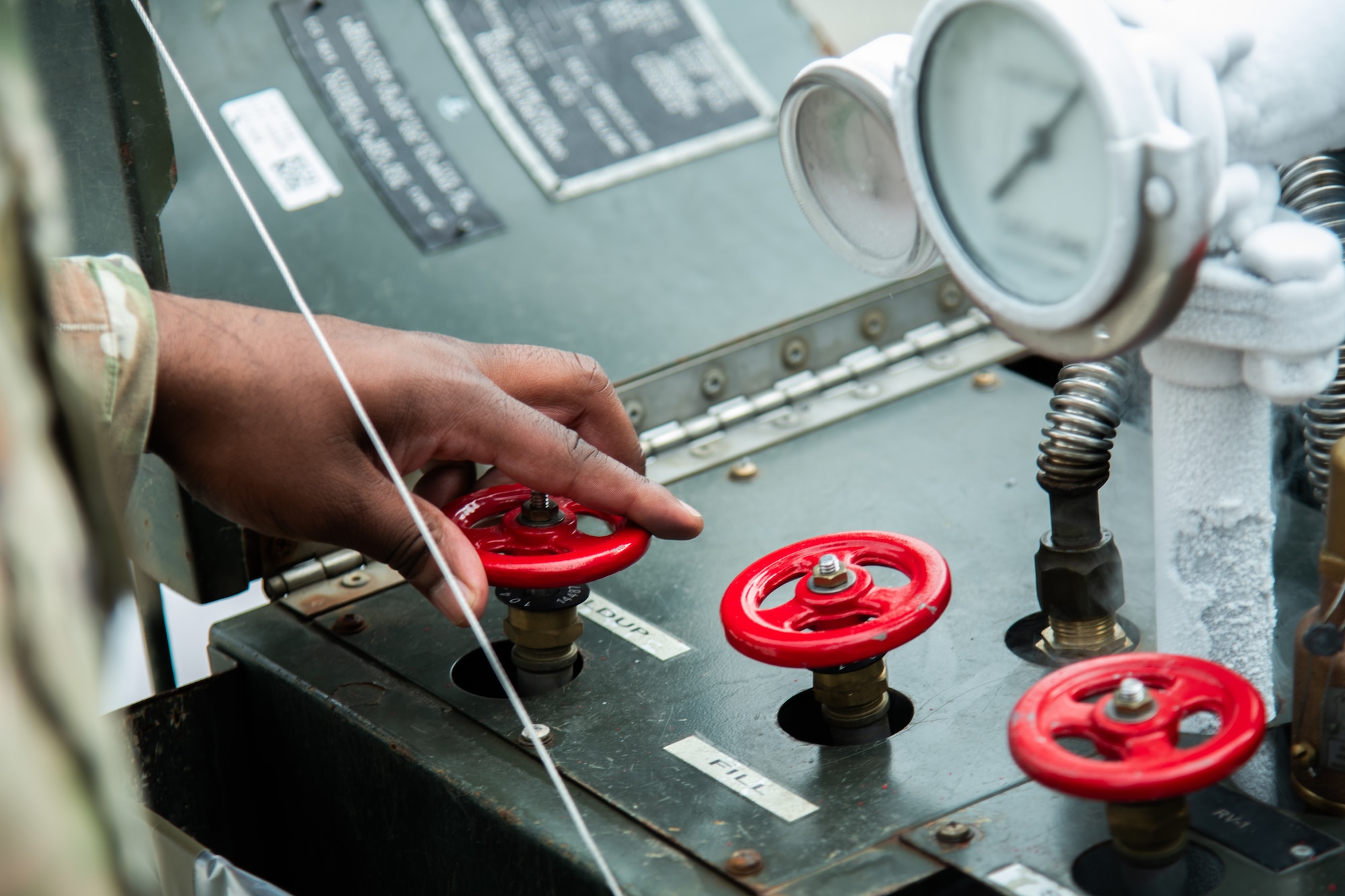 A hand turns a dial on a Liquid Oxygen Cart with red knobs.