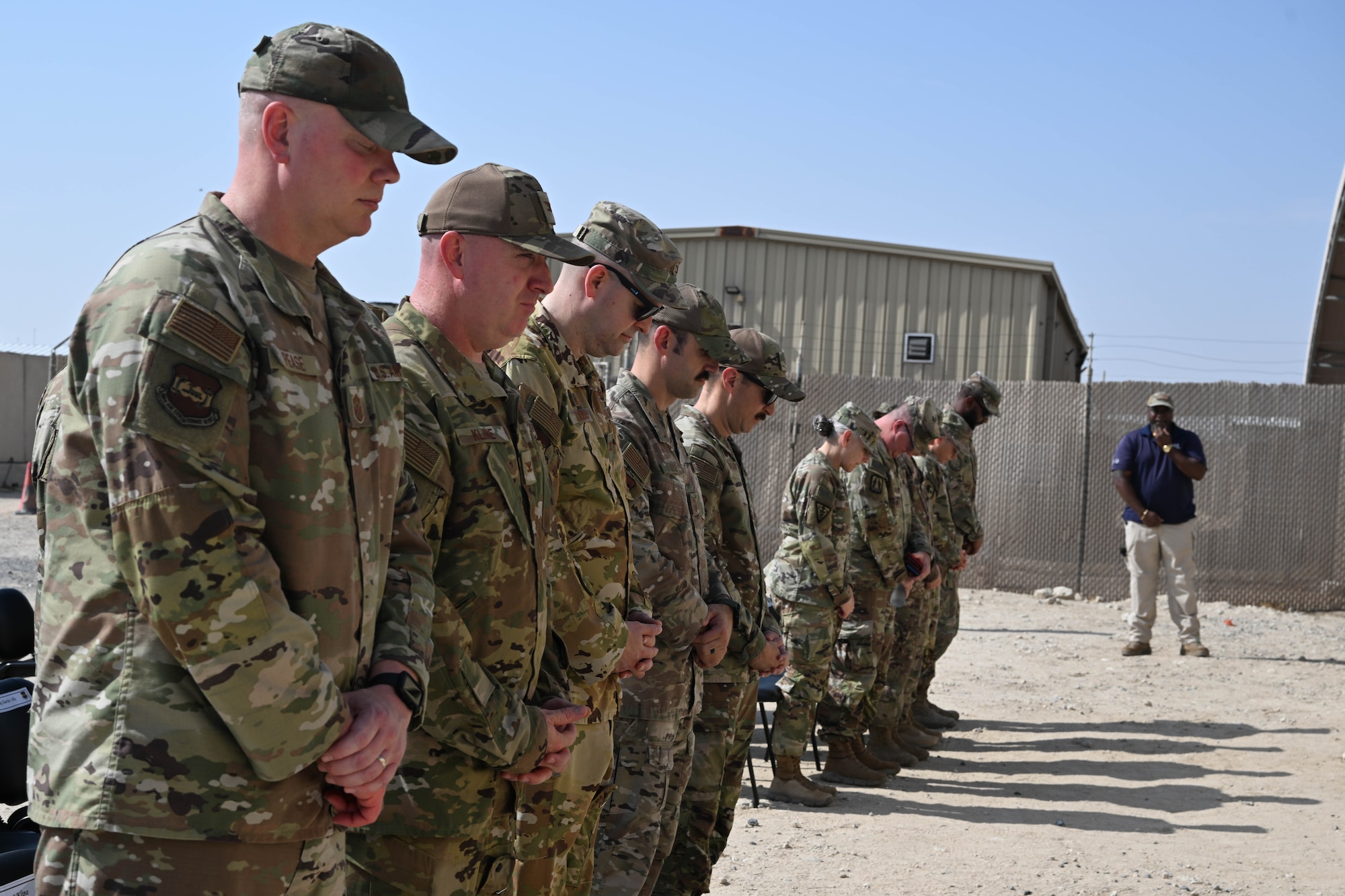 People in uniform bow their heads.