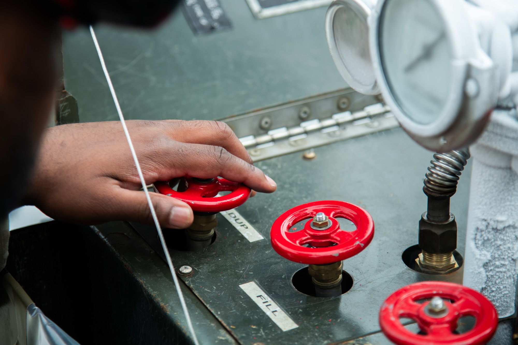 A hand turns a dial on a Liquid Oxygen Cart with red knobs.