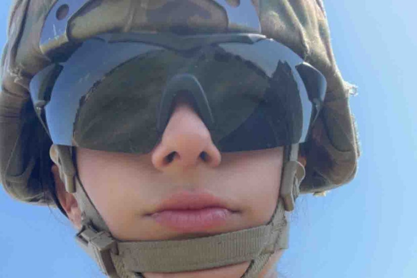 A soldier looks through dark eye protection at the camera.