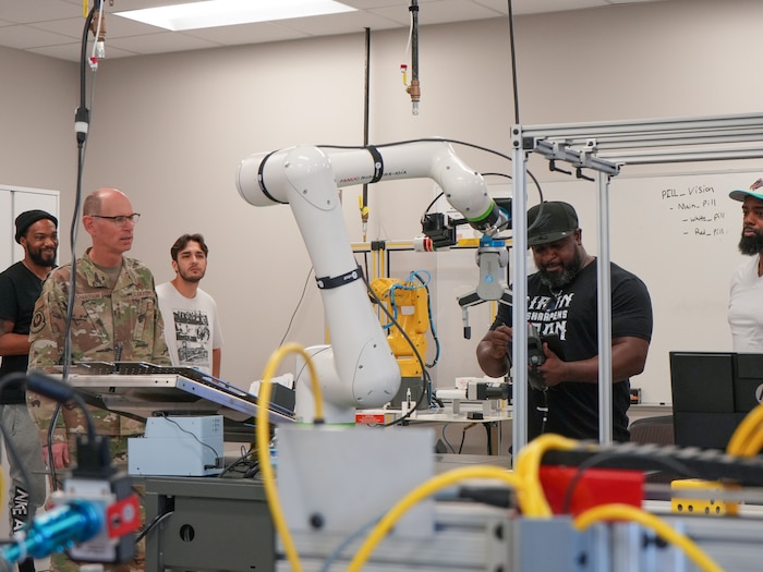 Photo shows people watching a man input information into a machine