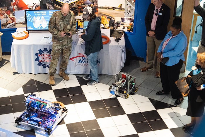 Photo shows two people working remote controlled robots