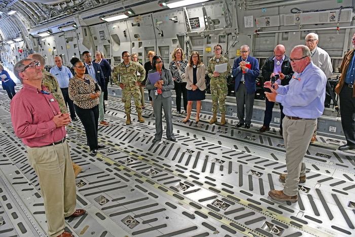 Photo shows a group of people talking to each other inside an aircraft