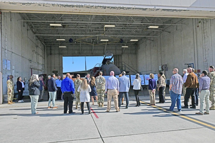 Photo shows group of people looking inside hangar containing an aircraft