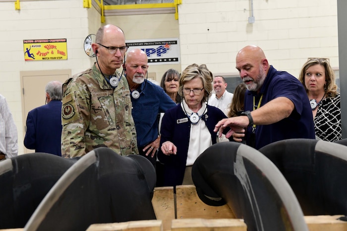Photo shows group of people looking at propeller on a rack