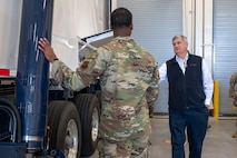An Airman speaks to a man about a military vehicle.