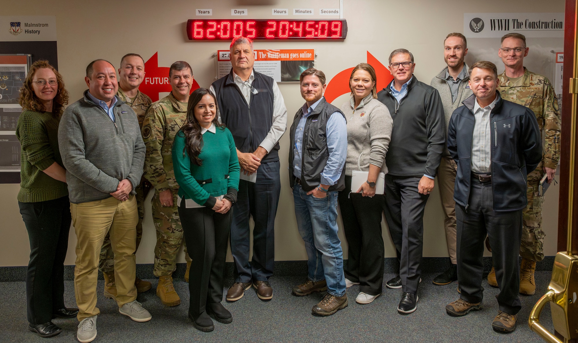 A group of people pose for a photo in front of a clock.
