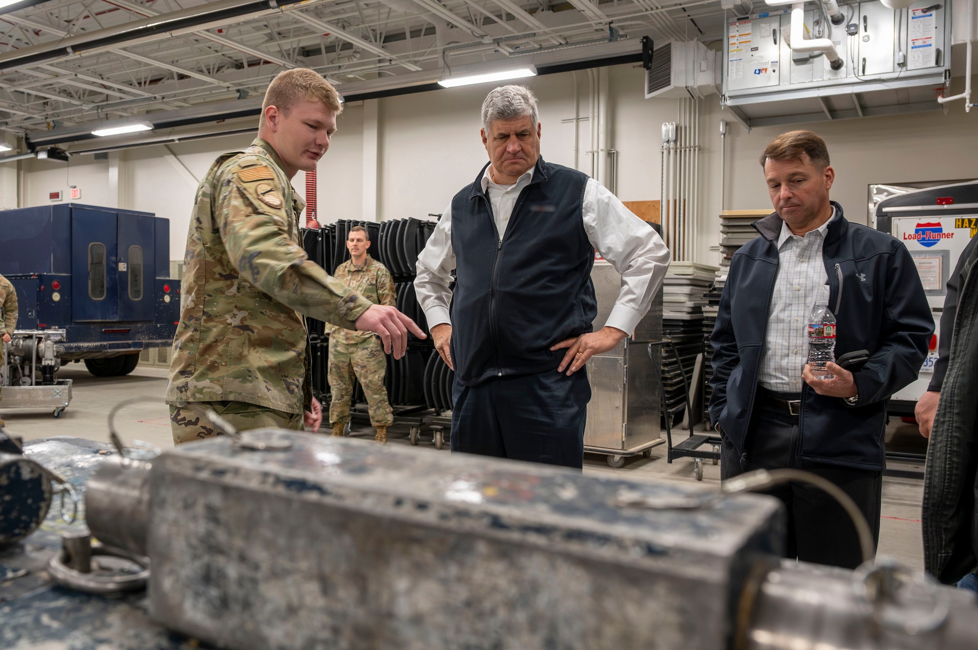 Airman points out an object to two people.