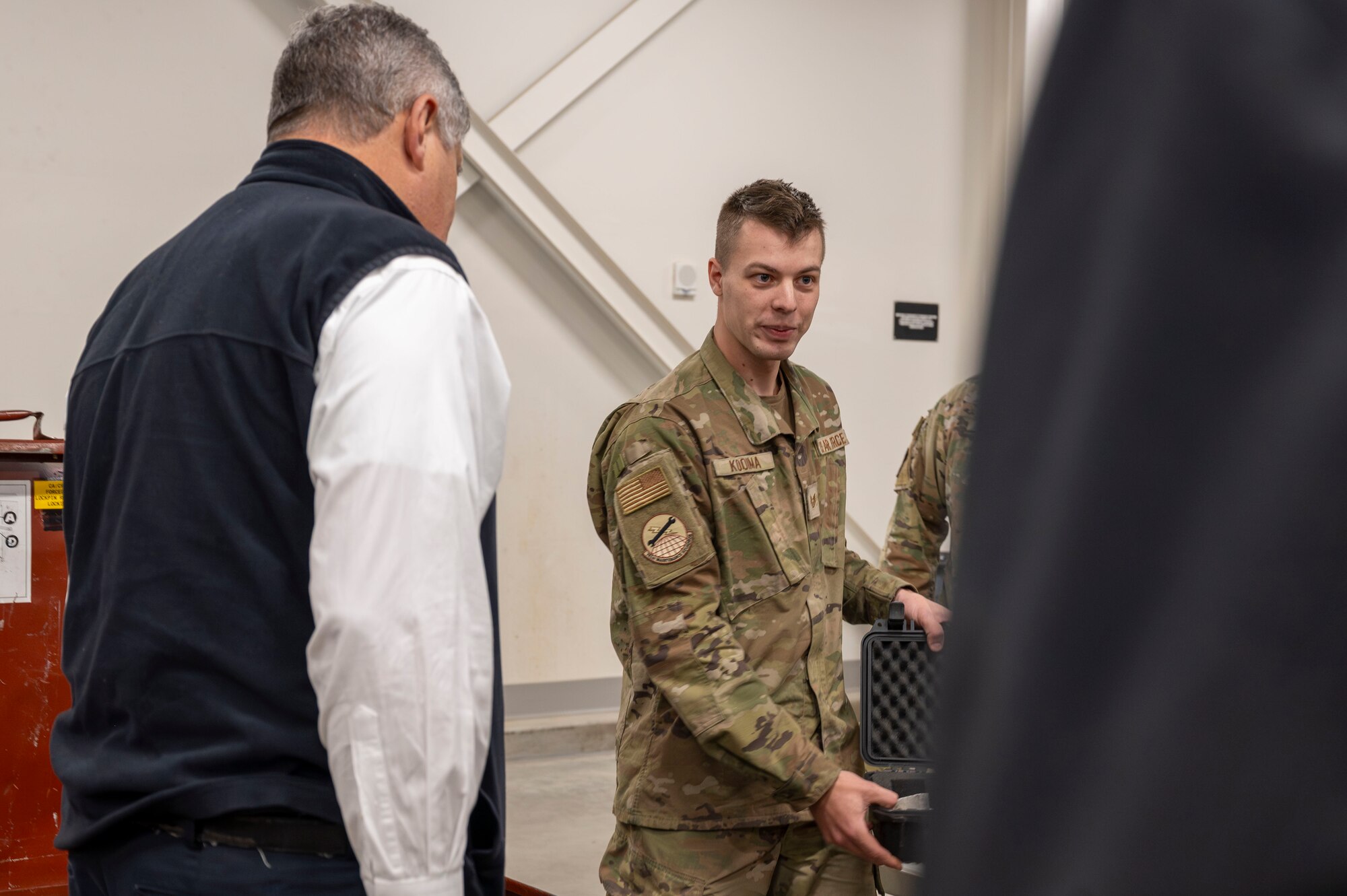 Airman shows object to group of people.