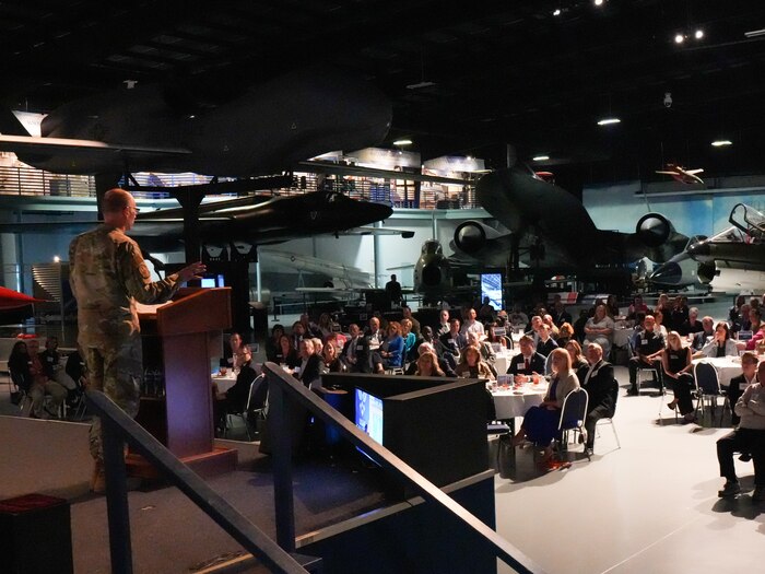 Photo shows man on stage speaking to group of people
