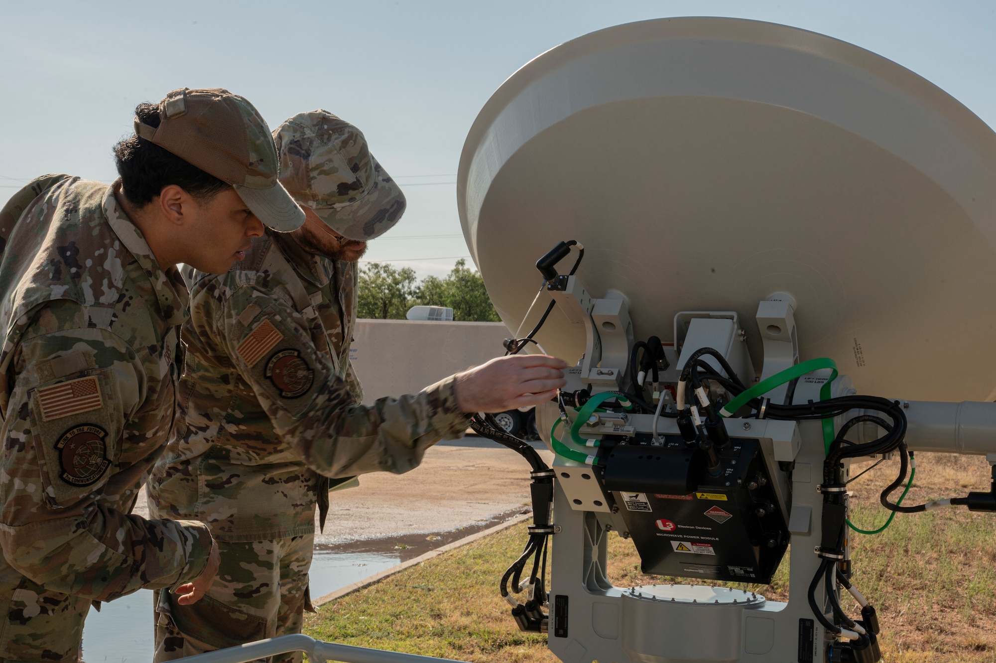 U.S. Air Force Airman 1st Class Michael Cruse, 7th Communications Squadron network infrastructure technician, and Tech Sgt. Anthony Forrest, 7th CS NCO in charge of radio transmission, reboot the Global Aircrew Strategic Network Terminal antenna control system at Dyess Air Force Base, Oct. 31, 2024. The GASNT is a transportable satellite dish with several computer base stations transmitting and receiving emergency action messages. (U.S. Air Force photo by Senior Airman Alondra Cristobal Hernandez)