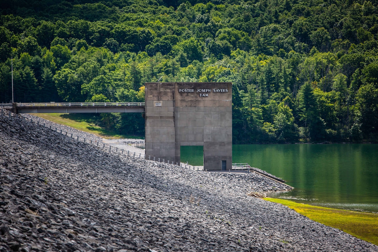A concrete section of a dam sits near water.