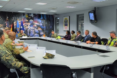 A group of people sit around a large conference table talking.