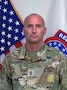 Photo of Command Sgt. Maj.posing for command photo in front of U.S. flag and United States Recruiting Command (USAREC) flag.